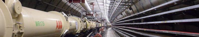A gently curving corridor full of pipes and cables -- a photo of the decommissioned HERA accelerator ring at DESY in Hamburg, Germany